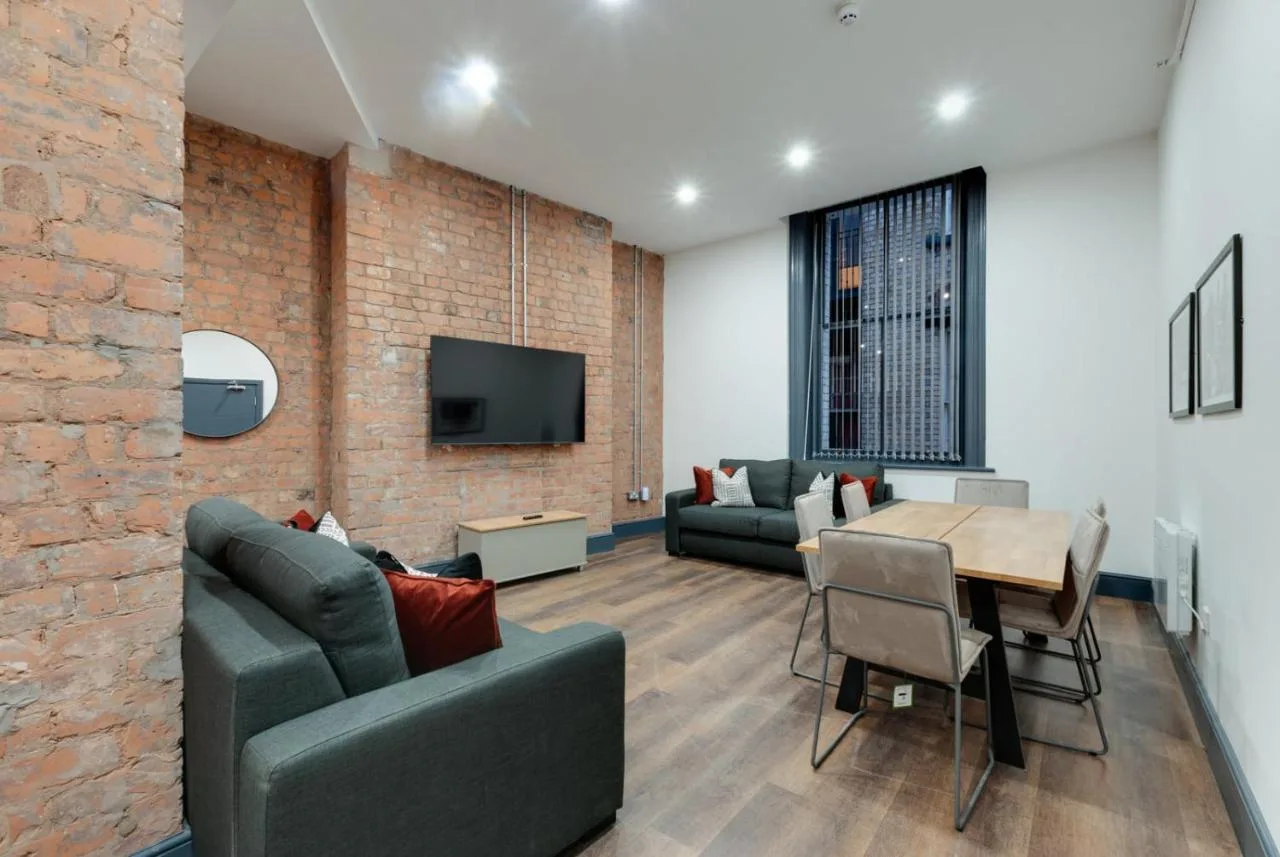 a living room with a table and a brick wall at Harrisons Aparthotel Liverpool in Liverpool